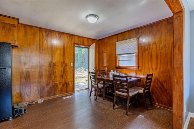 dining space featuring baseboards, visible vents, wood finished floors, and wood walls