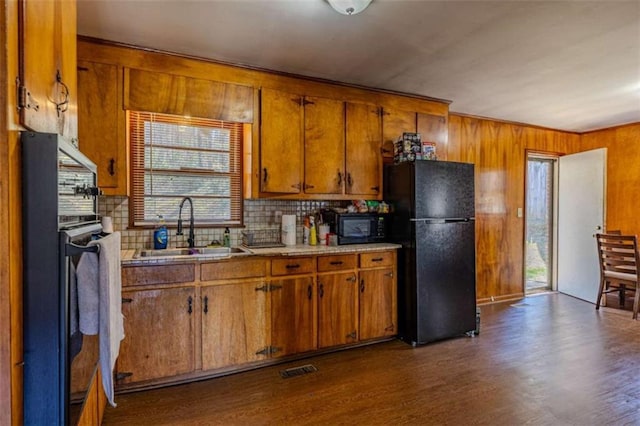 kitchen featuring brown cabinets, black appliances, a sink, and dark wood-style flooring