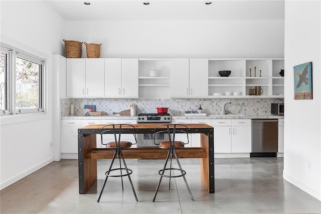 kitchen featuring open shelves, concrete floors, appliances with stainless steel finishes, and a sink