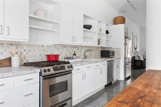 kitchen with a sink, backsplash, stainless steel appliances, and open shelves