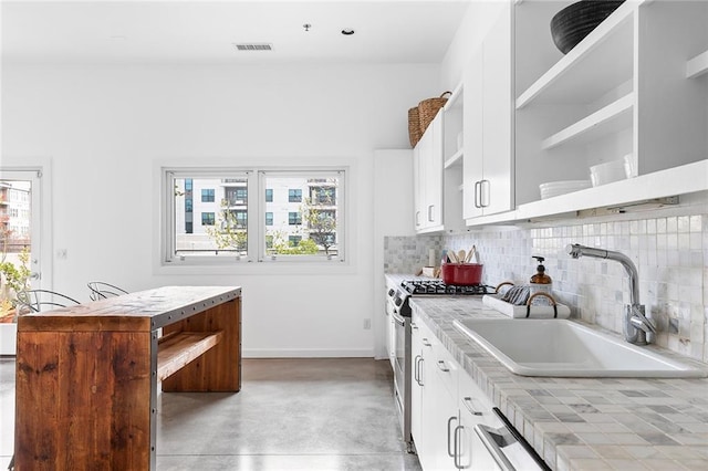 kitchen with visible vents, open shelves, a sink, tasteful backsplash, and stainless steel range with gas stovetop