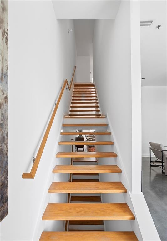 stairway featuring visible vents and finished concrete flooring