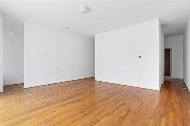 empty room with light wood-style flooring and baseboards