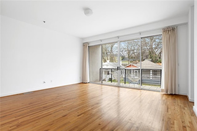 spare room featuring visible vents, baseboards, and hardwood / wood-style floors