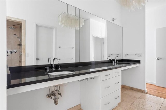 full bathroom featuring a sink, baseboards, double vanity, and tile patterned floors