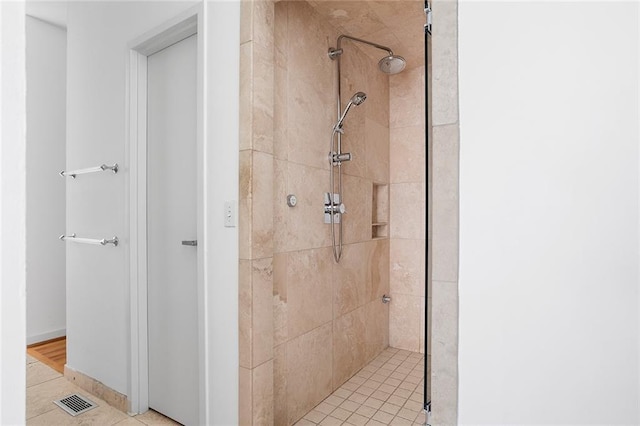 bathroom featuring visible vents, tiled shower, and baseboards