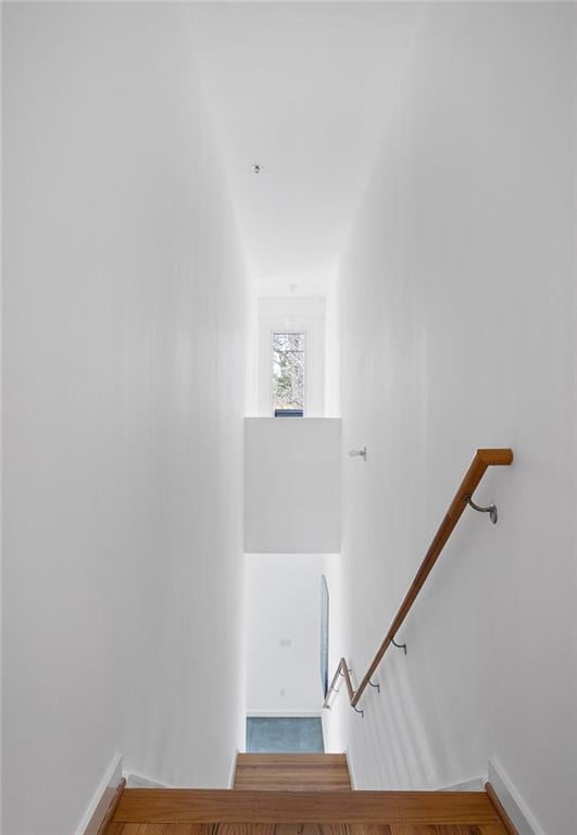 staircase featuring wood finished floors and baseboards