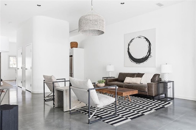 living area featuring visible vents, baseboards, and finished concrete flooring