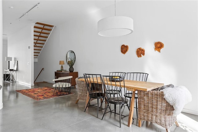 dining room featuring rail lighting, concrete floors, and baseboards