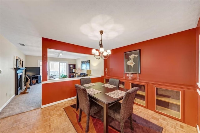 dining room with a chandelier, a fireplace, and baseboards