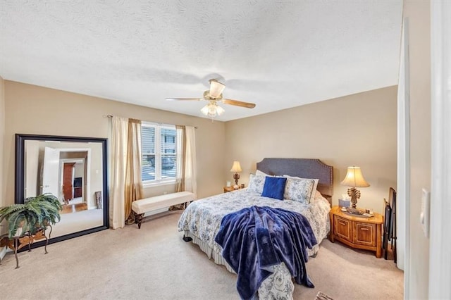 bedroom with light colored carpet, a ceiling fan, and a textured ceiling