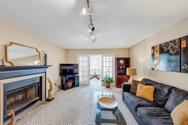 carpeted living area with rail lighting, a fireplace, a textured ceiling, and baseboards
