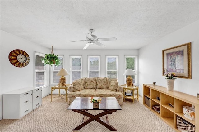 living area featuring a ceiling fan, light carpet, and a textured ceiling