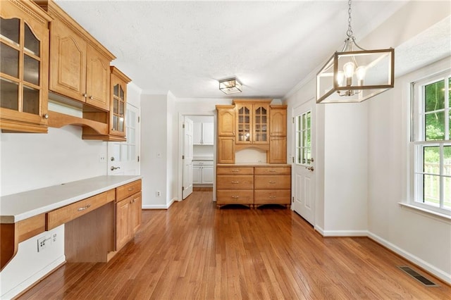 4135 Shoshone Valley Rd, Marietta, GA 30068 - kitchen with ornamental molding, a chandelier, light wood-type flooring, glass insert cabinets, and light countertops