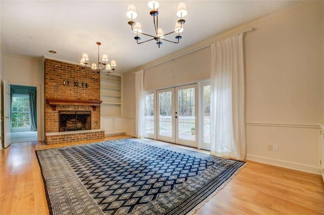 living room featuring plenty of natural light, built in features, french doors, and a chandelier