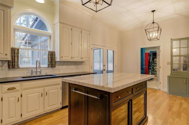 kitchen with sink, an inviting chandelier, a center island, light wood-type flooring, and decorative backsplash