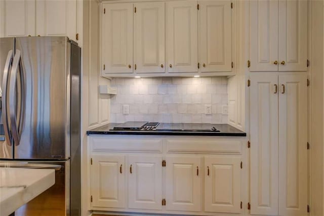 kitchen featuring stainless steel refrigerator, black electric cooktop, backsplash, and white cabinets