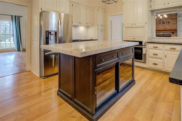 kitchen featuring white cabinetry, stainless steel appliances, a center island, and light hardwood / wood-style floors