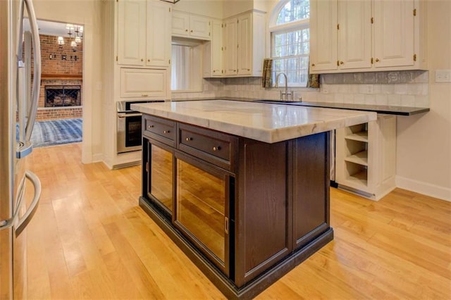 kitchen with white cabinetry, a kitchen island, sink, and a fireplace