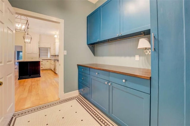 kitchen featuring butcher block counters, hanging light fixtures, light tile patterned floors, and blue cabinetry