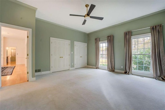 unfurnished bedroom with ceiling fan, light colored carpet, and ornamental molding