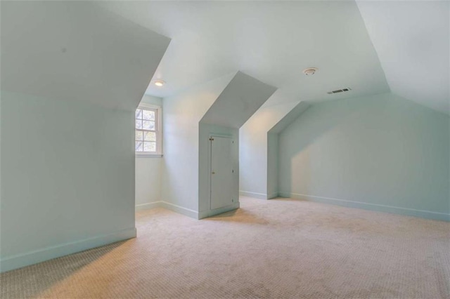 additional living space featuring light colored carpet and vaulted ceiling