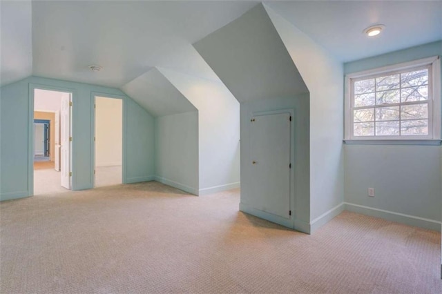 additional living space with vaulted ceiling and light carpet