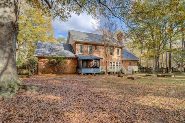 rear view of house featuring a sunroom and a deck