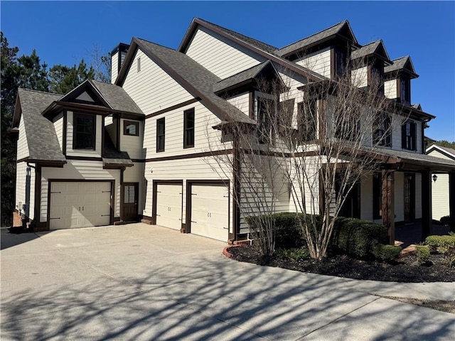 view of front of home with a garage, a chimney, concrete driveway, and roof with shingles