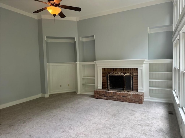 unfurnished living room featuring a brick fireplace, ceiling fan, carpet flooring, and crown molding