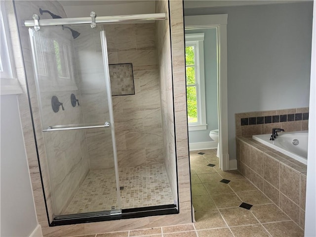 bathroom featuring tile patterned flooring, a stall shower, toilet, a garden tub, and baseboards