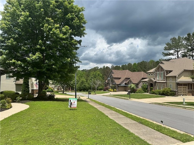 view of asphalt street with sidewalks, street lights, curbs, and a residential view