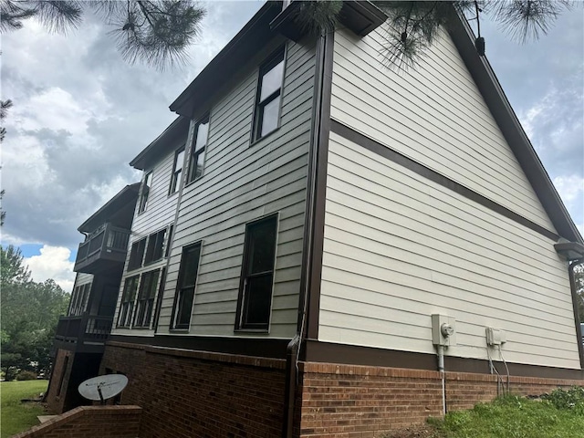 view of side of home with brick siding and a balcony