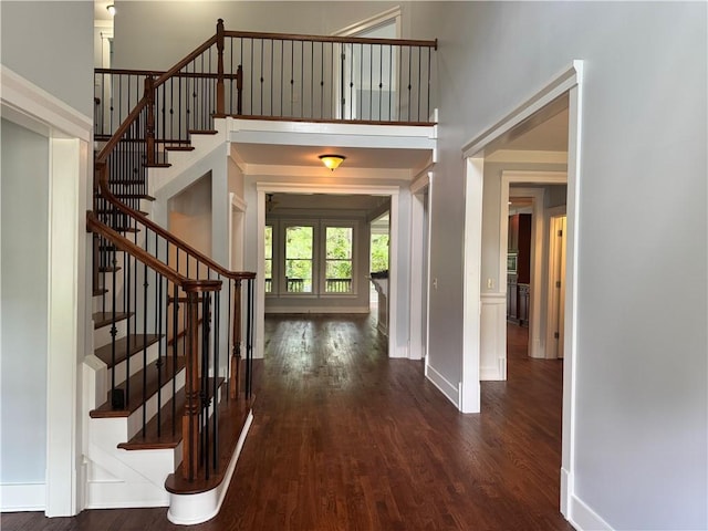 entryway with dark wood-type flooring, stairs, and baseboards