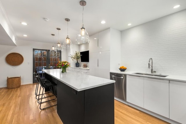 kitchen featuring dishwasher, a center island, white cabinetry, sink, and hanging light fixtures