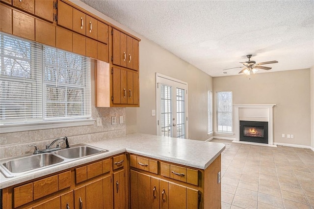 kitchen with sink, ceiling fan, a textured ceiling, decorative backsplash, and kitchen peninsula