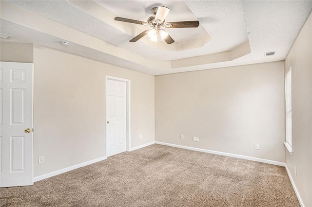 carpeted spare room featuring ceiling fan, a tray ceiling, and a textured ceiling