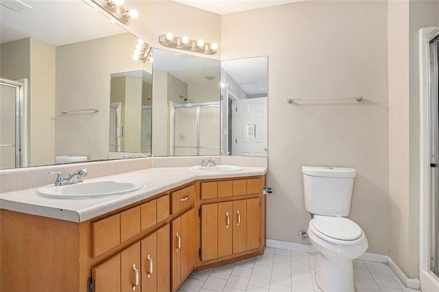 bathroom featuring a shower with door, vanity, tile patterned flooring, and toilet