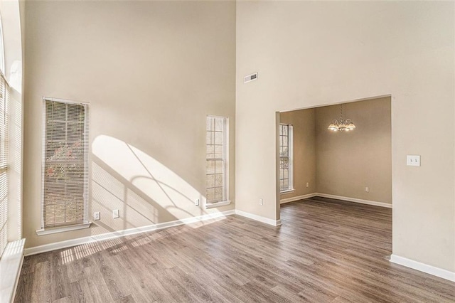 spare room featuring dark hardwood / wood-style flooring, a chandelier, and a high ceiling