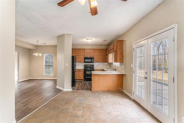 kitchen with ceiling fan with notable chandelier, decorative light fixtures, black appliances, kitchen peninsula, and french doors