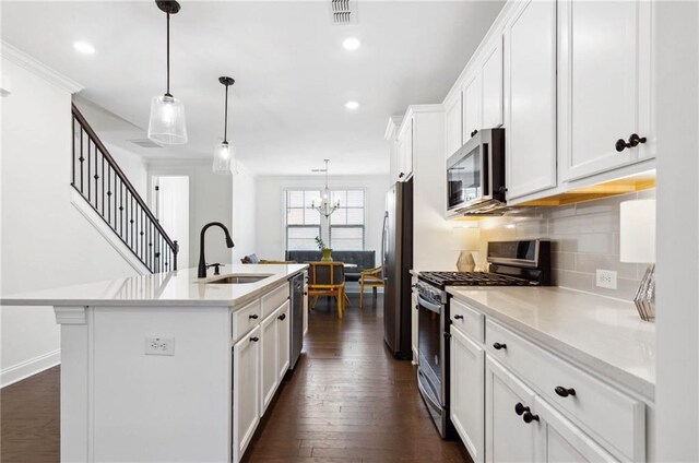 kitchen featuring dark hardwood / wood-style floors, a kitchen island with sink, sink, hanging light fixtures, and stainless steel appliances