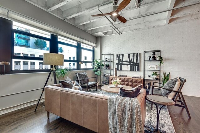 living area featuring baseboards, brick wall, a ceiling fan, and wood finished floors