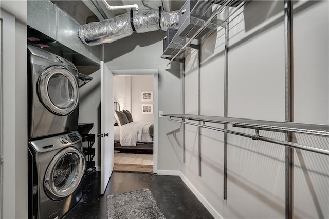 laundry area with baseboards, laundry area, and stacked washer / drying machine