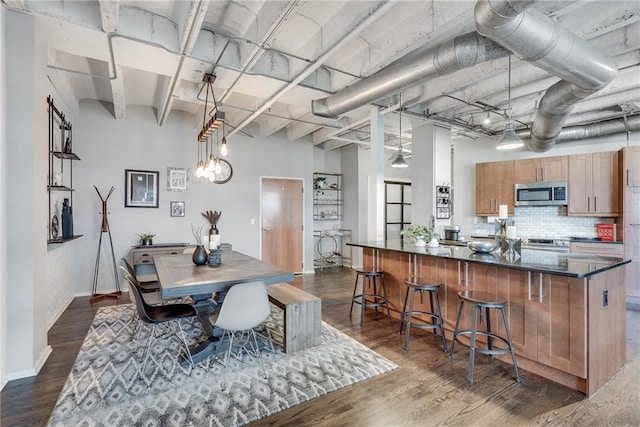 dining space with dark wood-style floors, a towering ceiling, and baseboards