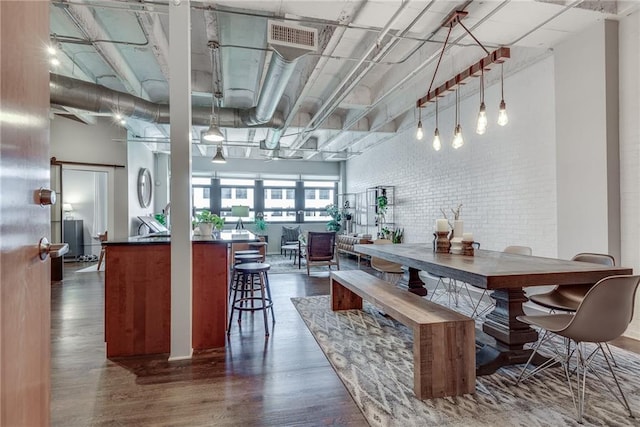 dining room with dark wood-type flooring, a high ceiling, and brick wall