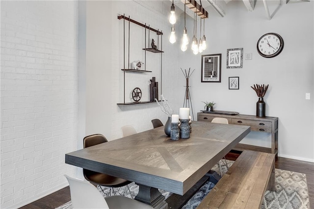 dining room featuring brick wall, baseboards, and wood finished floors