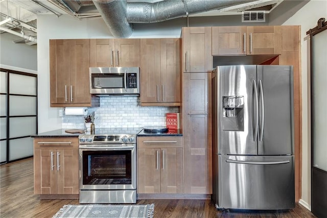 kitchen with dark wood-style floors, stainless steel appliances, visible vents, and decorative backsplash