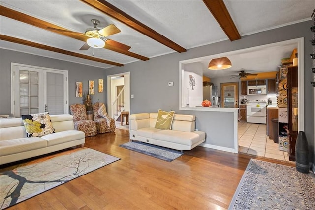 living room with french doors, beamed ceiling, and light wood-type flooring