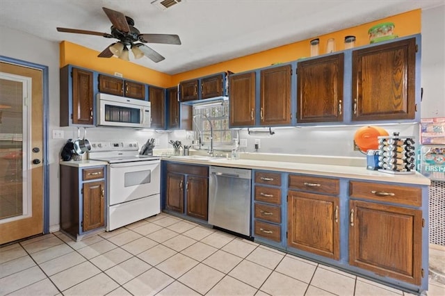 kitchen with white appliances, sink, ceiling fan, light tile patterned floors, and dark brown cabinetry