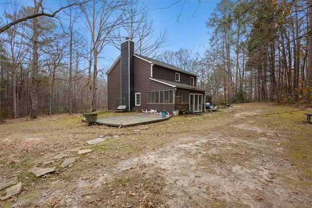 view of home's exterior with a sunroom and a wooden deck